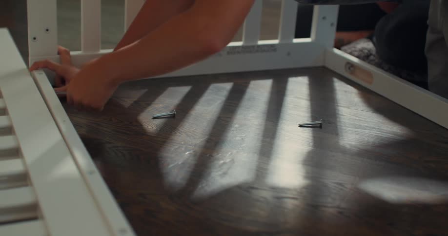 Hands of a person with a tool screwing a crib
