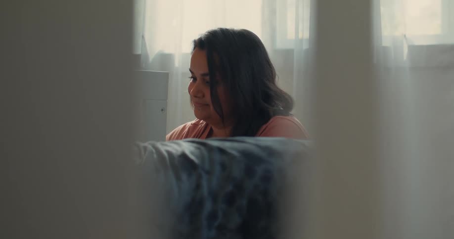 Woman sitting in a room and another person partially visible next to her