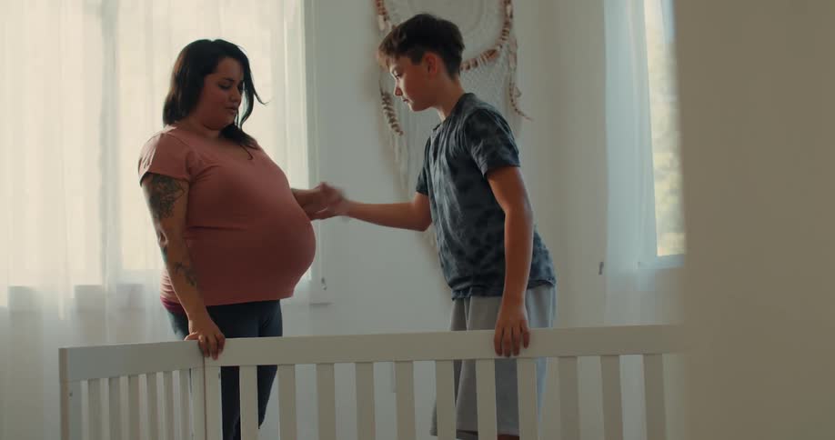Son helping pregnant mother to stand up