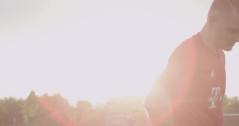A player on a soccer field is turning and walking under a bright sun