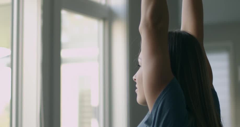 A woman is stretching while looking at the window