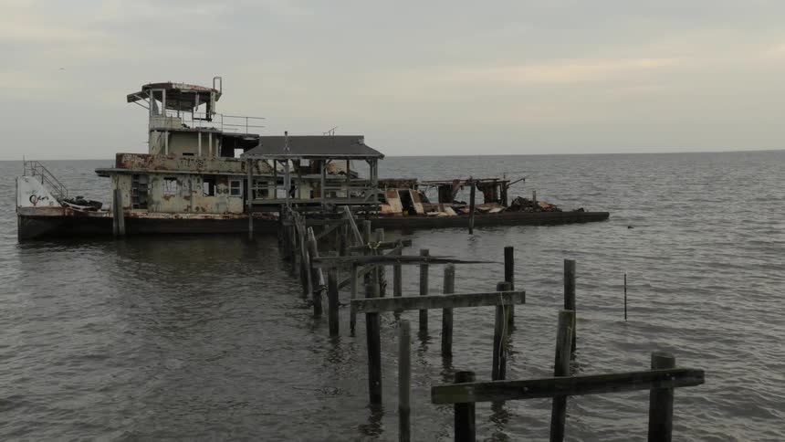 An old wreck of a boat moored at a broken down pier