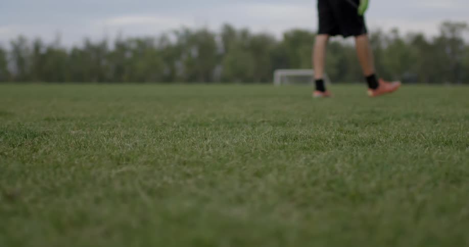A soccer player slowly walks on the grass
