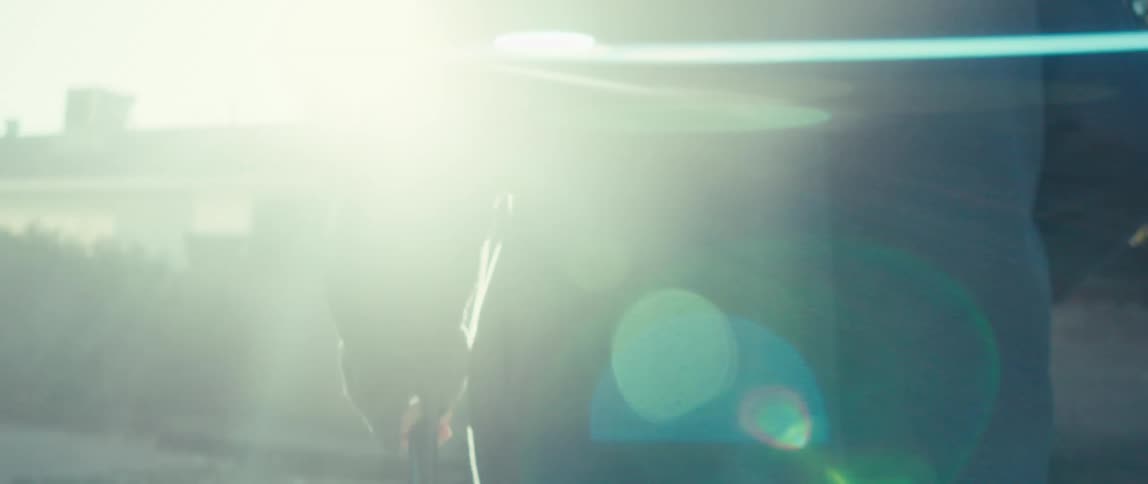 Closeup of an elderly persons arm walking with a cane in the yard with the sun shining through