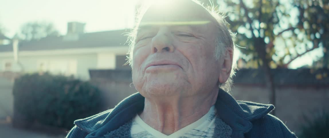 An elderly man relaxes on the backyard on a sunny day