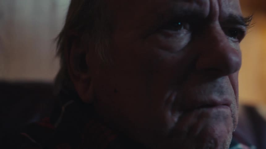 A man shakes his head while watching the television