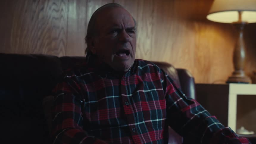 A man leans forward and yells at the television