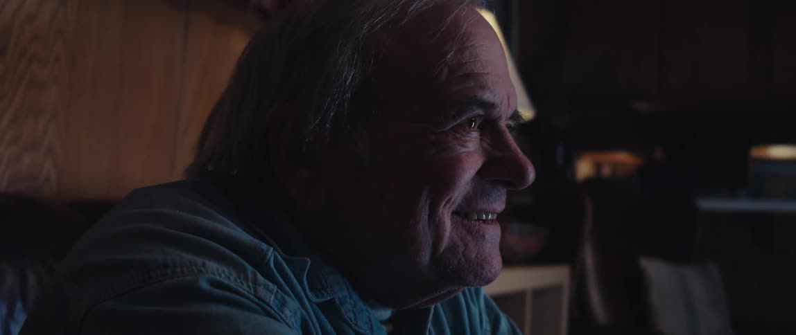 Elderly man sitting in a dark room smiling and having fun