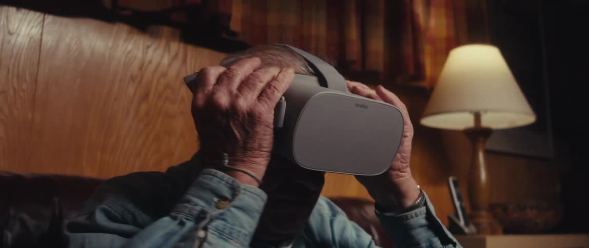 An elderly man sits on his couch and puts on a vr headset