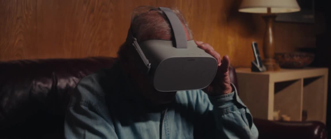 Elderly man sitting using virtual reality glasses and then taking off his glasses