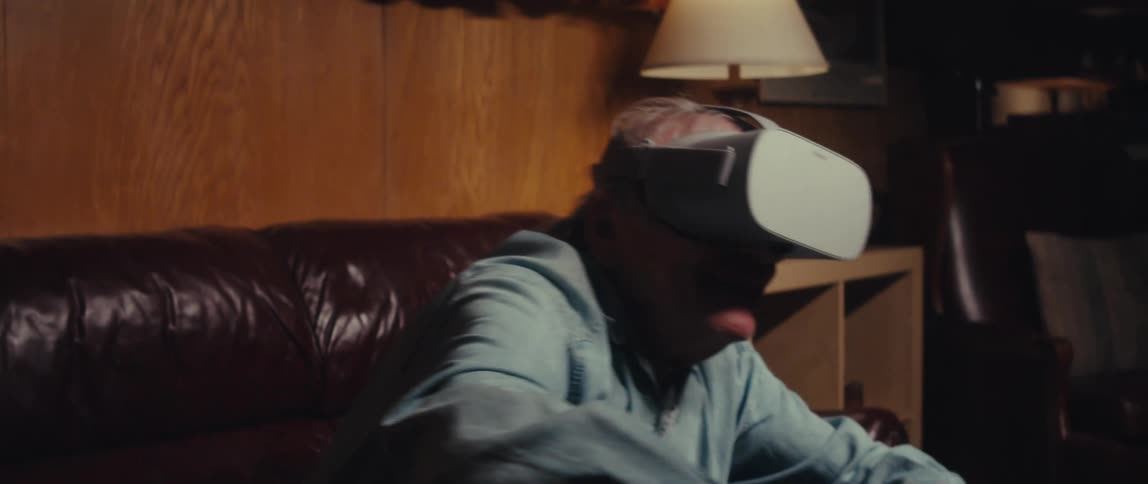 Elderly man sitting in an armchair having fun playing with augmented reality glasses