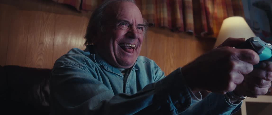 An elderly man is having fun playing video games at home