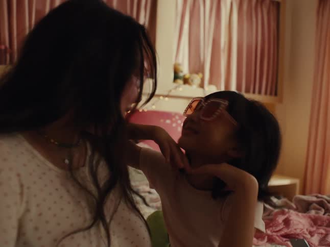 A teenage girl and a little girl putting glasses on their faces and then they look at each other and start making faces at each other playfully