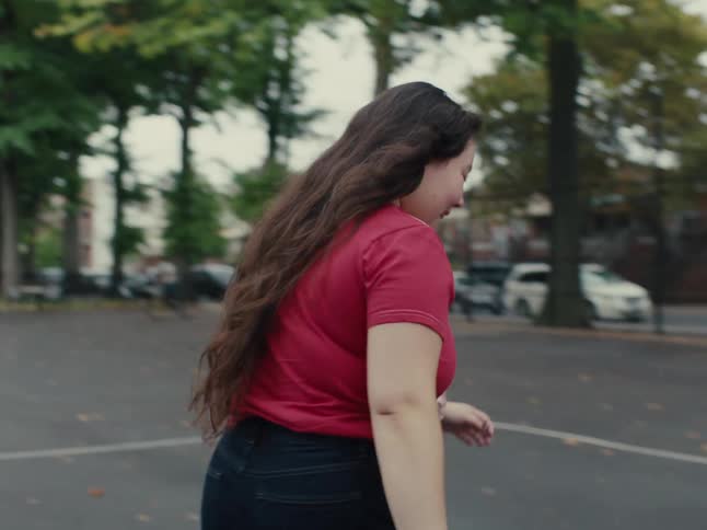 Teenage boy and girl on a court playing basketball outdoors