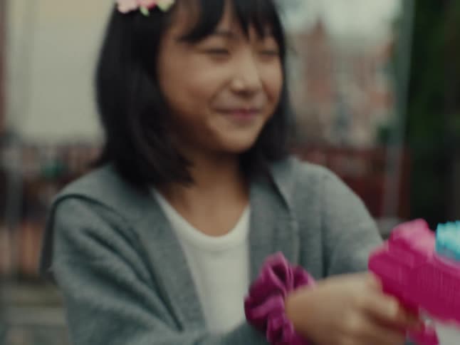 A girl plays with a colorful toy gun in a park