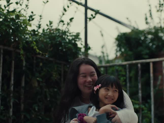 Two people likely siblings embrace and laugh joyfully outdoors