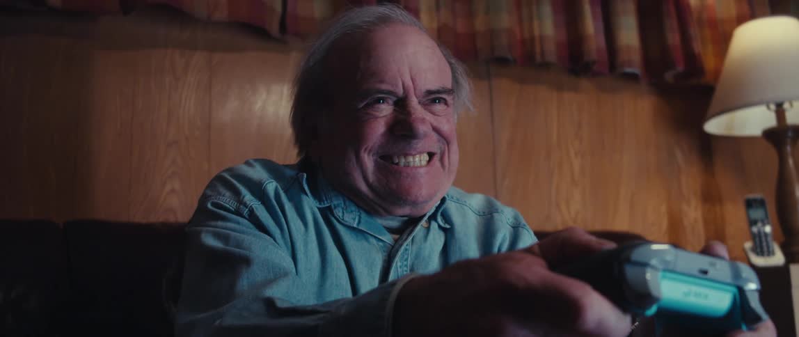 Man and old man sitting in an armchair having fun playing video games