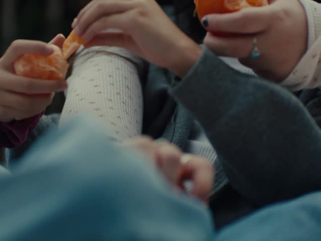 Hands of two people peeling an orange
