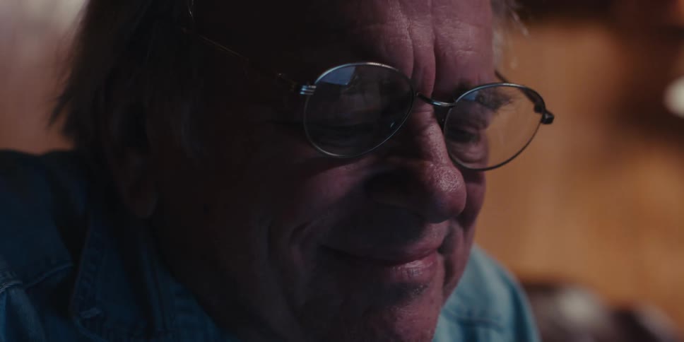 Happy elderly man looking down putting on his glasses