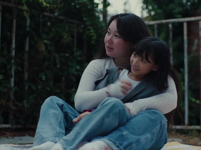 Older sister cuddling with younger sister having fun outdoors