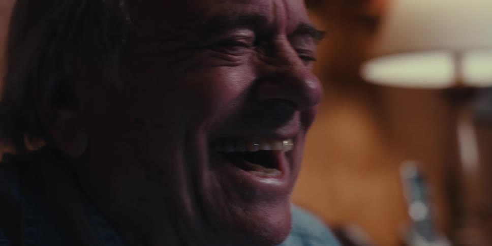 Close up of an elderly man laughing in a dimly lit room