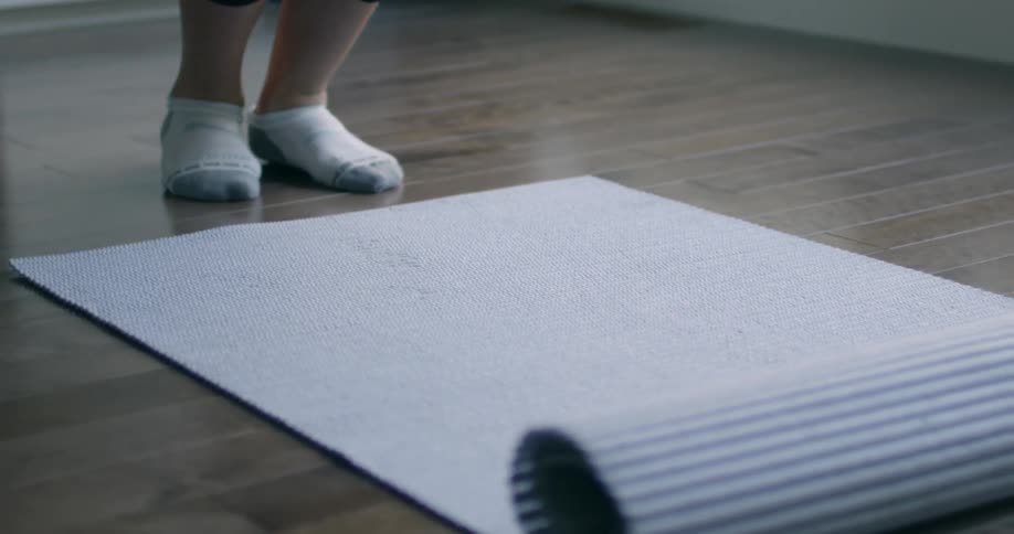A woman rolls out a yoga mat