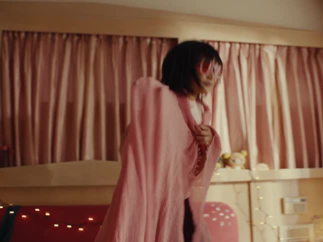 Young teenage girl and a child on top of the bed playing with blankets in a bedroom