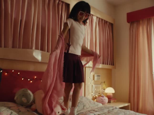 Young woman sitting on the bed using a fan and a child on the bed playing