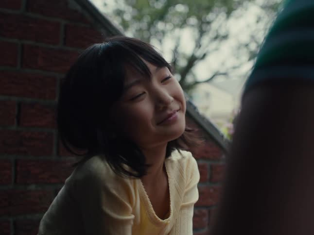 Girl sitting outdoors while thinking smiles at her mother and holds her hand
