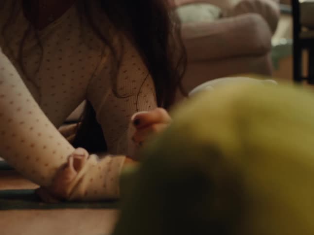 A resting girl gets hit with a stuffed animal and she laughs