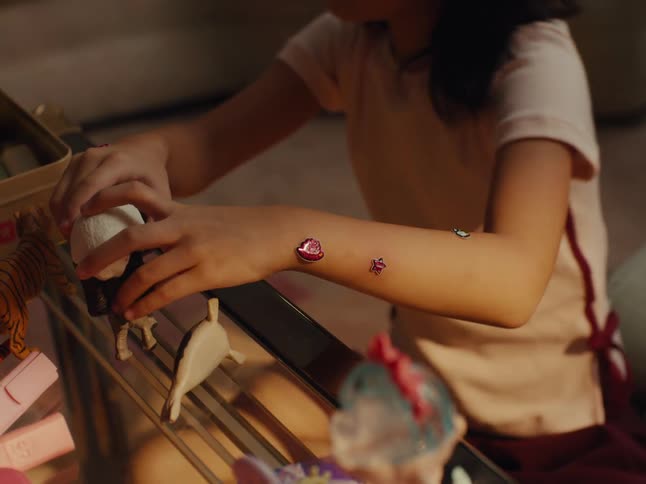 Arms of a girl playing with toys on the table