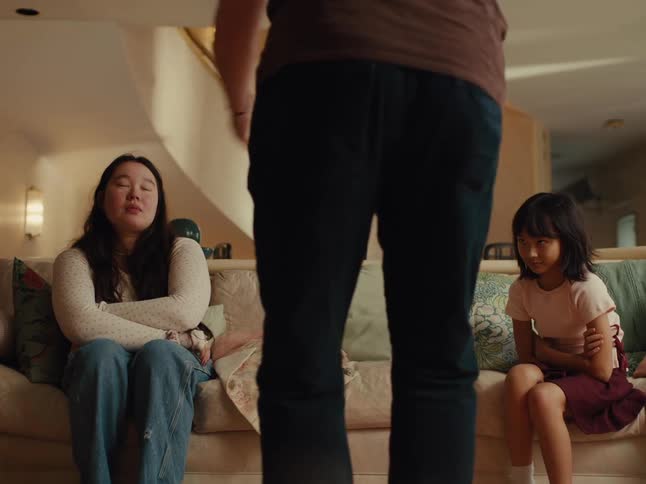 Adult man fighting with teenage girl and her younger sister who are sitting on a couch in the living room