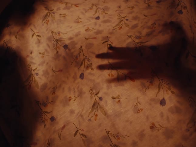 The shadow of a persons hands across a white cloth
