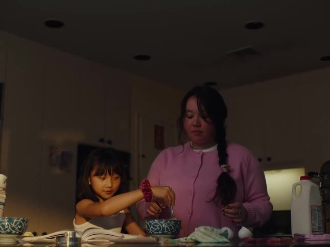 A teenager and child cook in the kitchen