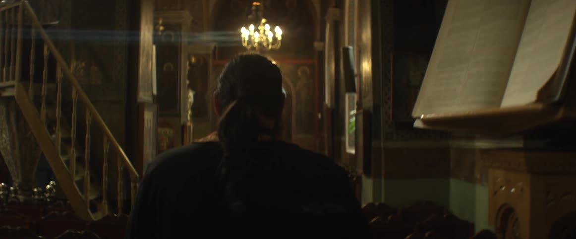 A priest walks in a narrow hall of a church