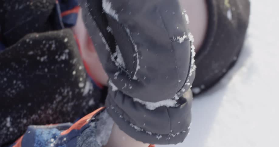 A boy is laying in the snow playing