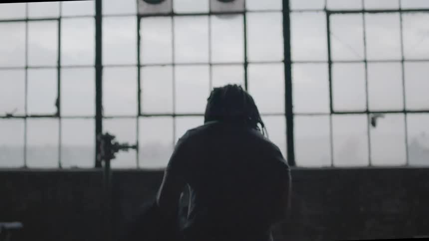 A man taking a shirt off in a building with a lot of windows