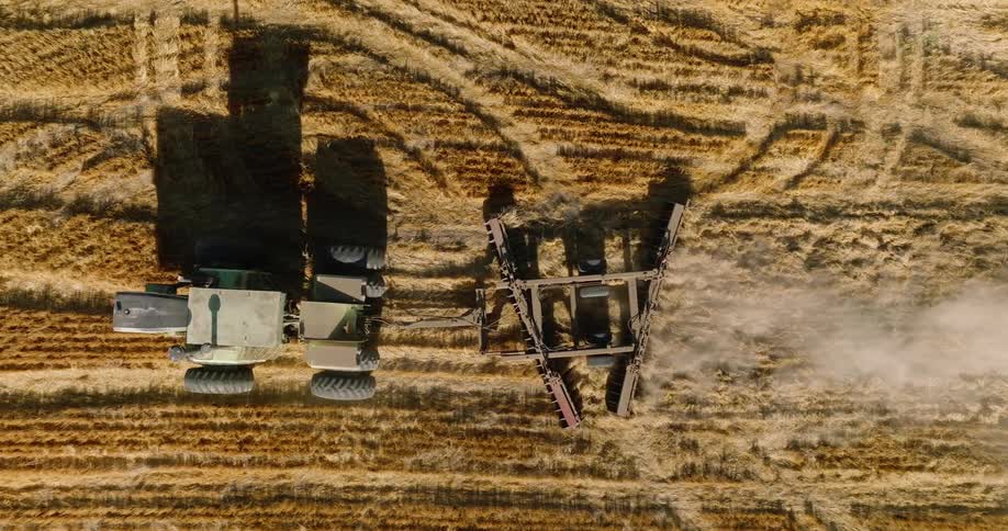 An aerial view of a tractor pulling a large plow through a field