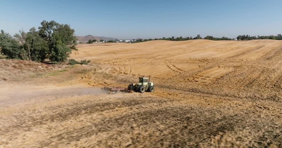 A tractor is working the field on a farm