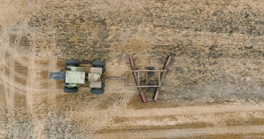 A tractor drags a plow through a field