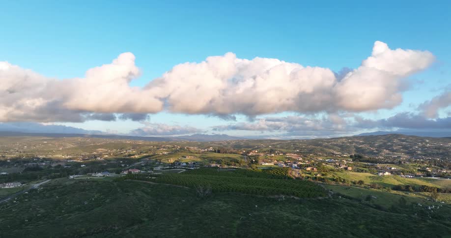 A landscape of a large flat region of green vegetation and white clouds in the sky