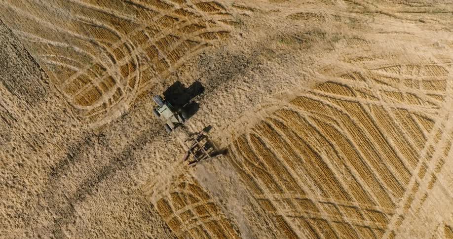 An aerial clip of a tractor on a farm field