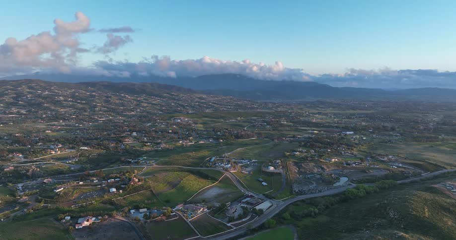 An aerial view of a rural town set in a green field with small hills