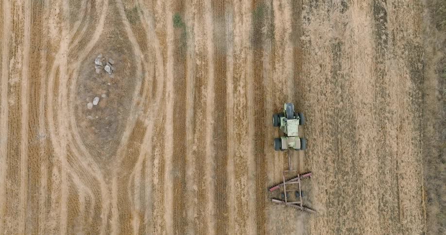 Aerial view of an agricultural machine passing through a field