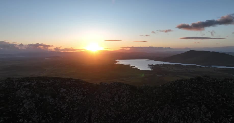 Aerial panorama of a mountain range with a lake and the sunset on the horizon