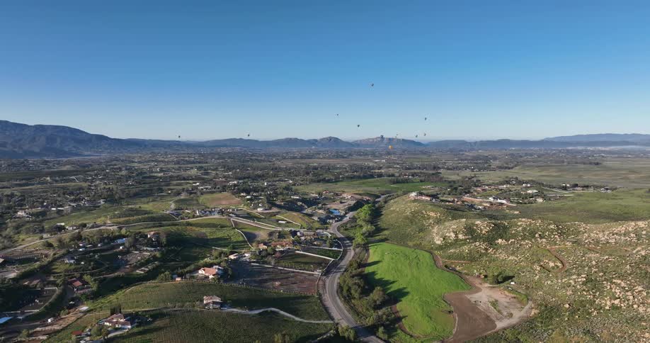 A scenic aerial view of a rural area with rolling hills farms and a clear blue sky