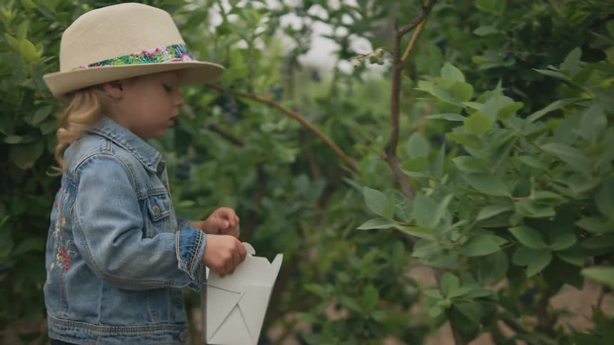 A footage of a female child wearing a hat in the garden
