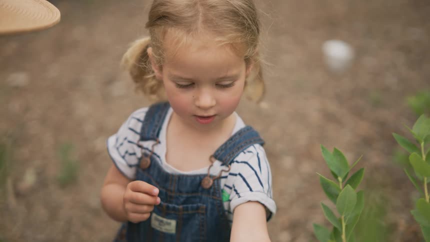 Little girl next to her mother outdoors eating fruit straight from the tree