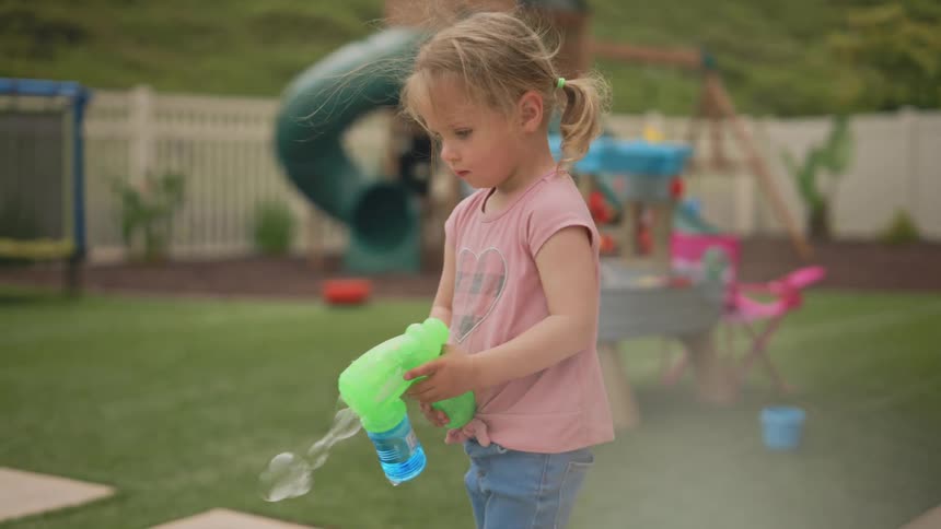 Little girl in a backyard playing with a bubble gun