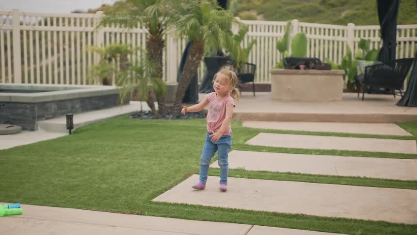 A girl stands in a luxurious backyard pointing up
